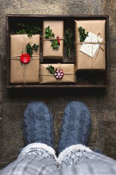 Feet with warm winter socks standing in front of Christmas gifts