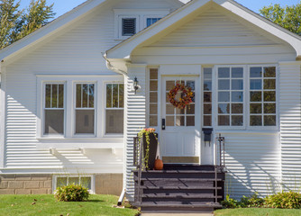 Exterior street view of cute bungalow home decorated for fall with Autumn wreath and pumpkin...