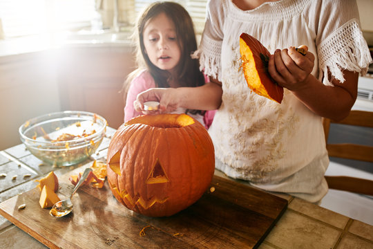 fun activity - mother and daughter having fun carving pumpkin into jack o lantern for halloween