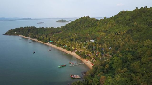 Aerial camera slowly pushes in on an island paradise in beautiful sun light. Continuation of prior clip.