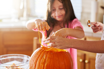 little girl with slime on hands from pumpkin to make jack o lantern for halloween