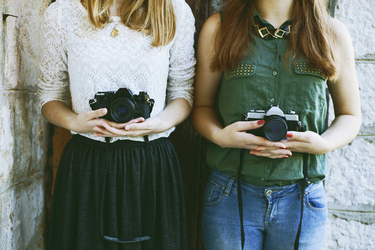 Two young woman photographers holding film cameras in hands