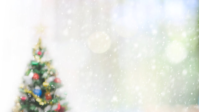 Blurred bokeh christmas tree with snowfall background for your text or advertising.