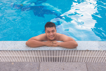 Good-looking man smiling and relaxing in pool