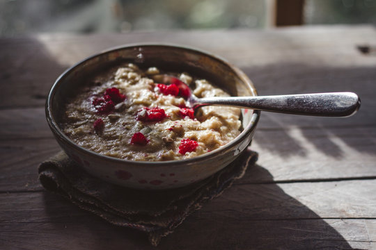 Porridge with raspberries in front of a window, cooling