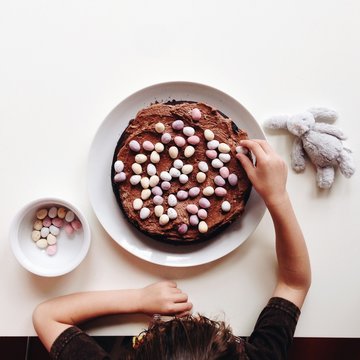 Overhead picture of a boy decorating a cake with chocolate eggs.