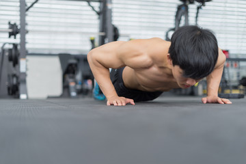 Fototapeta na wymiar Fitness man showing push up exercises in gym