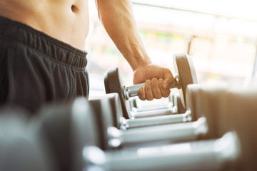 Fototapeta na wymiar Fitness man in training showing exercises with dumbbells in gym