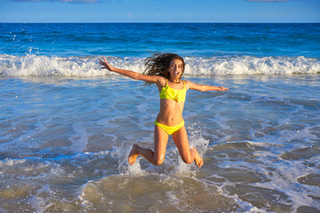 Bikini girl jumping in Caribbean sunset beach