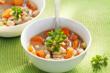 Vegetable soup with bean and carrots on green background