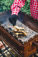 Hand puts small chips into fire of brazier close up