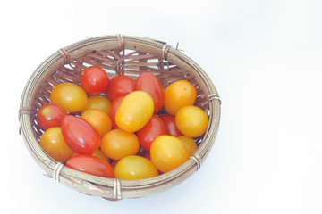 Small red cherry tomatoes inside a basket on isolated white background