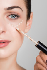 Makeup artist applying liquid tonal foundation on the face of the woman