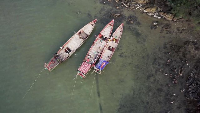 Aerial camera straight down looking at fisherman tied up to shoreline while they take a break and eat a lunch.