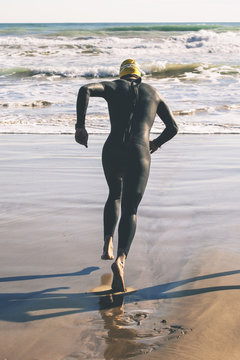 Triathlete running to the water on triathlon race.