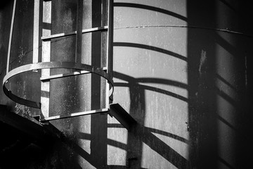 Shadows and lines cross over black and white photos of old industrial rusty tanks