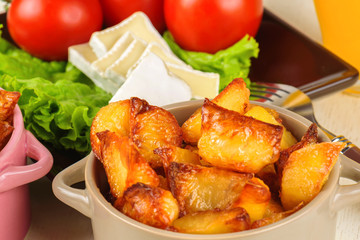 Breakfast from cheese, tomatoes, potatoes and all-over salad on a wooden table closeup.