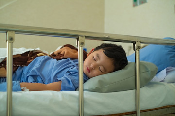 Sick Asian kid boy 2 years old lying sick in hospital bed.