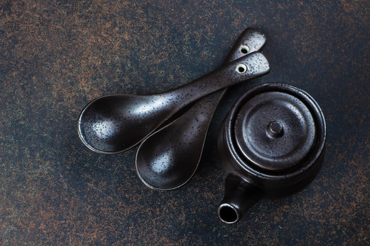 Japanese and Chinese food equipment on dark stone concrete table background. Spoons and kettle. Top view with copy space