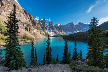 Fototapeta na wymiar Beautiful turquoise waters of the Moraine Lake at sunset with snow-covered peaks above it in Rocky Mountains, Banff National Park, Canada.
