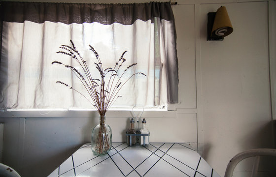a simple kitchen table with a vase holding stems of long grass