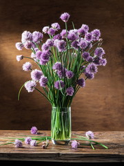 Bouquet of onion (chives) flowers in the vase on the wooden table.