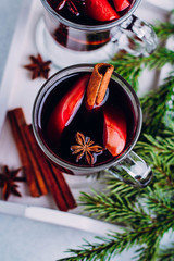 Christmas Winter Hot Drink. Glasses of hot mulled wine with spices and sliced orange and apple on stone concrete table background. Top view