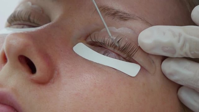 Woman on the procedure for eyelash extensions, eyelashes lamination. Beauty spa salon