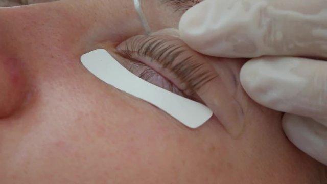 Woman on the procedure for eyelash extensions, eyelashes lamination. Beauty spa salon