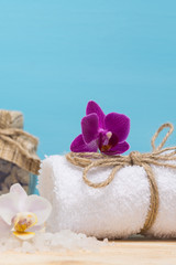 Fototapeta na wymiar towel with pink flower for spa treatments, on a blue background