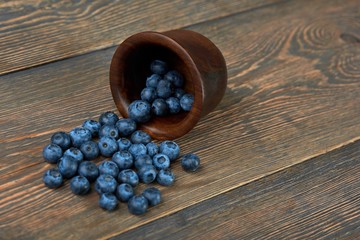 Obraz na płótnie Canvas CLose up of a handful of delicious fresh blueberries on the wooden table copyspace background layout vitamins health organic natural berries dieting nutrition breakfast concept.