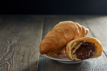 Close up of  delicious croissants with chocolate filling on a plate on a wooden surface copyspace sweet dessert cacao pastry cooking breakfast snack concept.