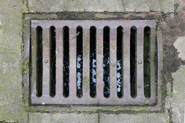 Old rusty iron grille of the rain sewer system of the city