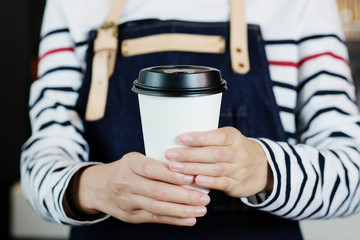Barista hands holding a take away coffee cup with at cafe counter background, small business owner, food and drink industry concept