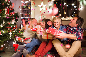 Senior friends next to Christmas tree with presents.