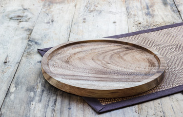 Empty wooden plate on wood table. Copy space. Wood plate for food or vegetable serving to customers. A plate made from wood and widely used in vintage restaurant because looks beautiful and natural.