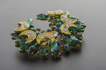 golden brooch with emeralds and diamonds isolated on black