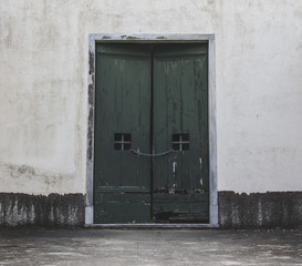 Fantastic old green wooden door located on a white stone building. - 177892340