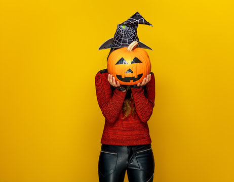 woman holding sad jack-o-lantern pumpkin in front of face