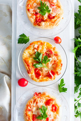 Mini pizza topped with cherry tomatoes ,ham and cheese