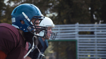 Side view of two American football players putting helmets on while preparing for game