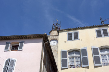 France, Provence, French Riviera, Draguignan, Lorgues: Old medieval steeple with clock and church bell surrounded by house facades. 