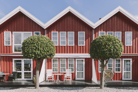 Back porch of three identical red and white wooden summer houses