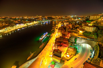 Fototapeta na wymiar Aerial view of Oporto skyline and Ribeira Waterfront from Dom Luis I Bridge at night. Picturesque urban cityscape of Porto in Portugal.Rabelo and tourist boats on Douro River. Porto colorful nightlife