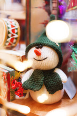 Christmas and New Year background with hand made toy - knitted snowman with red bells. Decorations for holiday celebration.