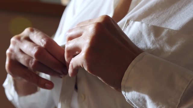 close-up, details. a woman buttoning the top button on a white shirt. 4k, slow motion