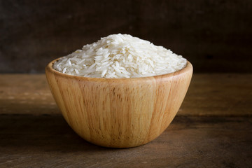 Jasmine rice in wooden bowl on rustic wood background