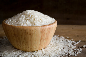 Jasmine rice in wooden bowl on rustic wood background