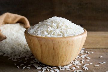 Jasmine rice in wooden bowl on rustic wood background