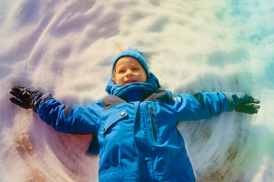 happy little boy play with snow make snow angel